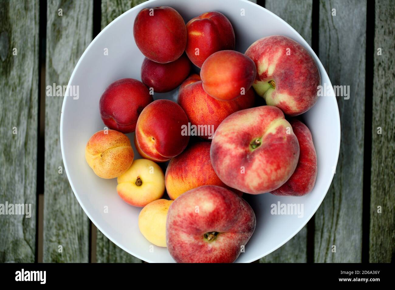Summer fruits in white bowl on wooden table view from above Stock Photo