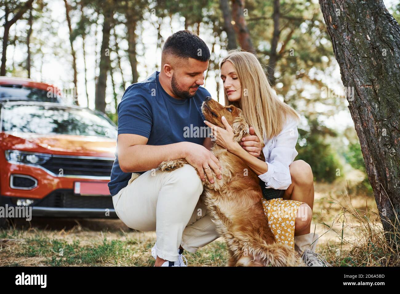 Couple with dog have weekend outdoors in the forest with car behind ...