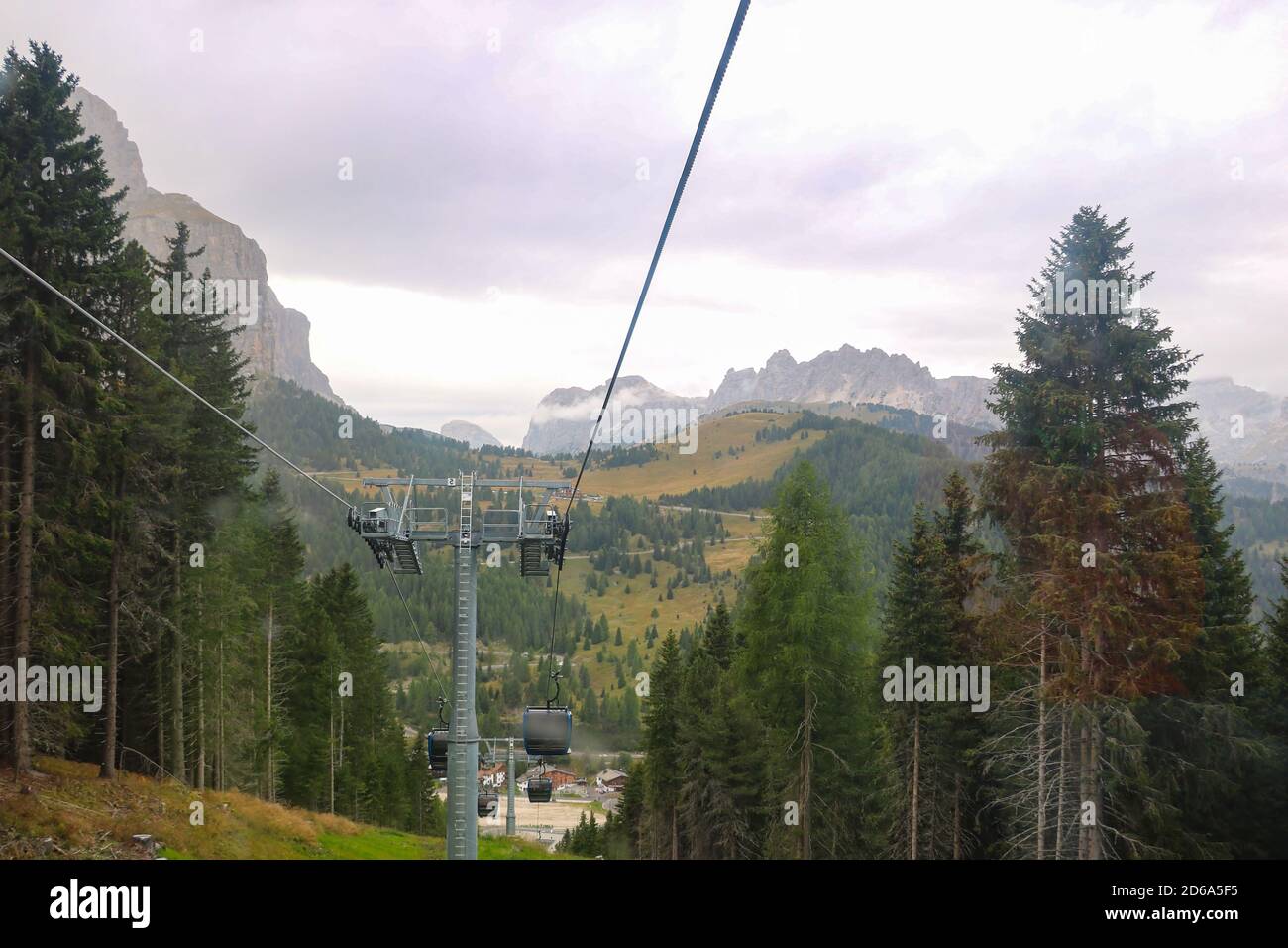 View from the cable car cabin to the village in the mountains and the Dolomites in Italy. Selective focus Stock Photo