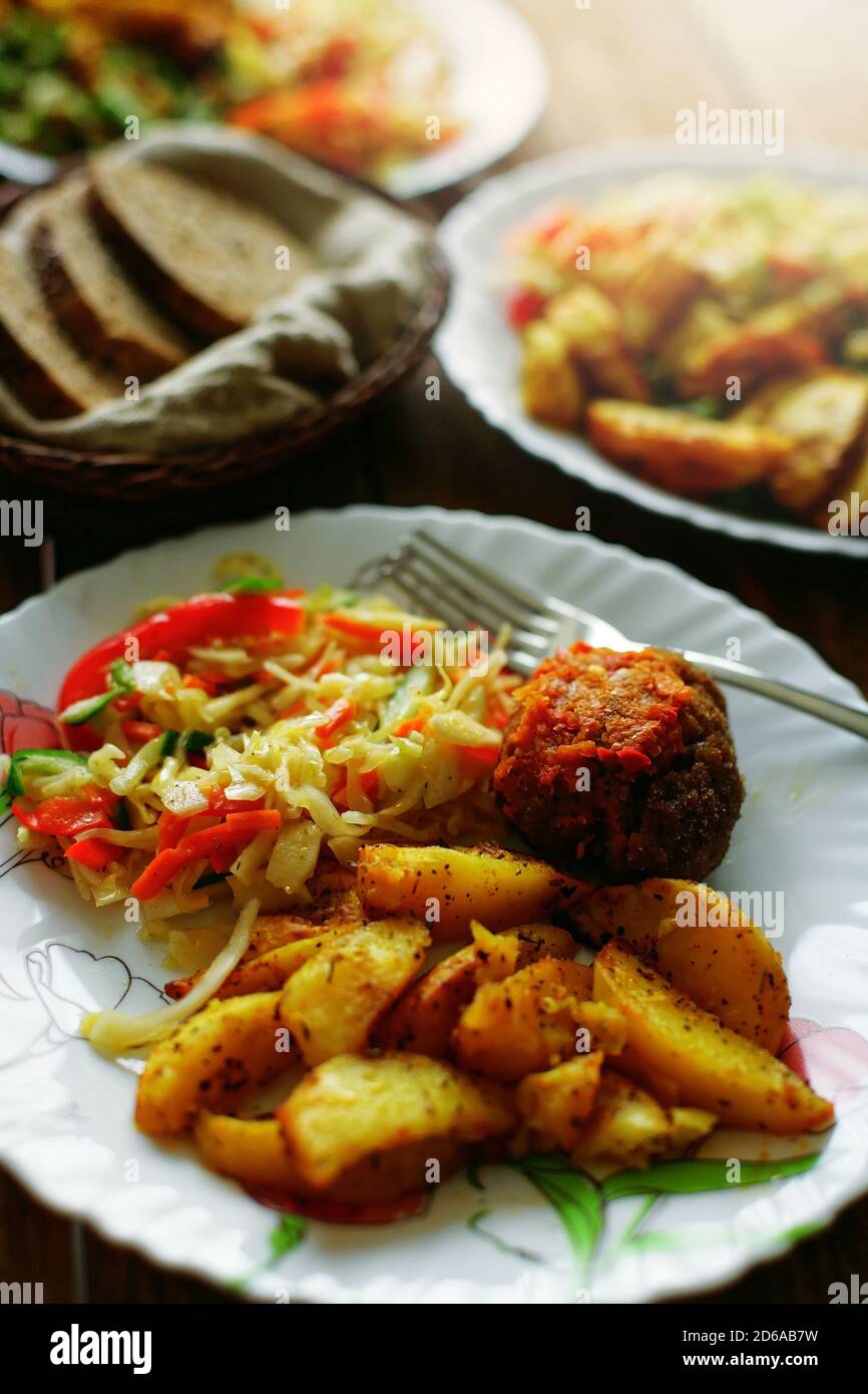 A simple meal on a plate at a diner. Salad, fried potatoes and meat cutlet. Quick and delicious lunch Stock Photo