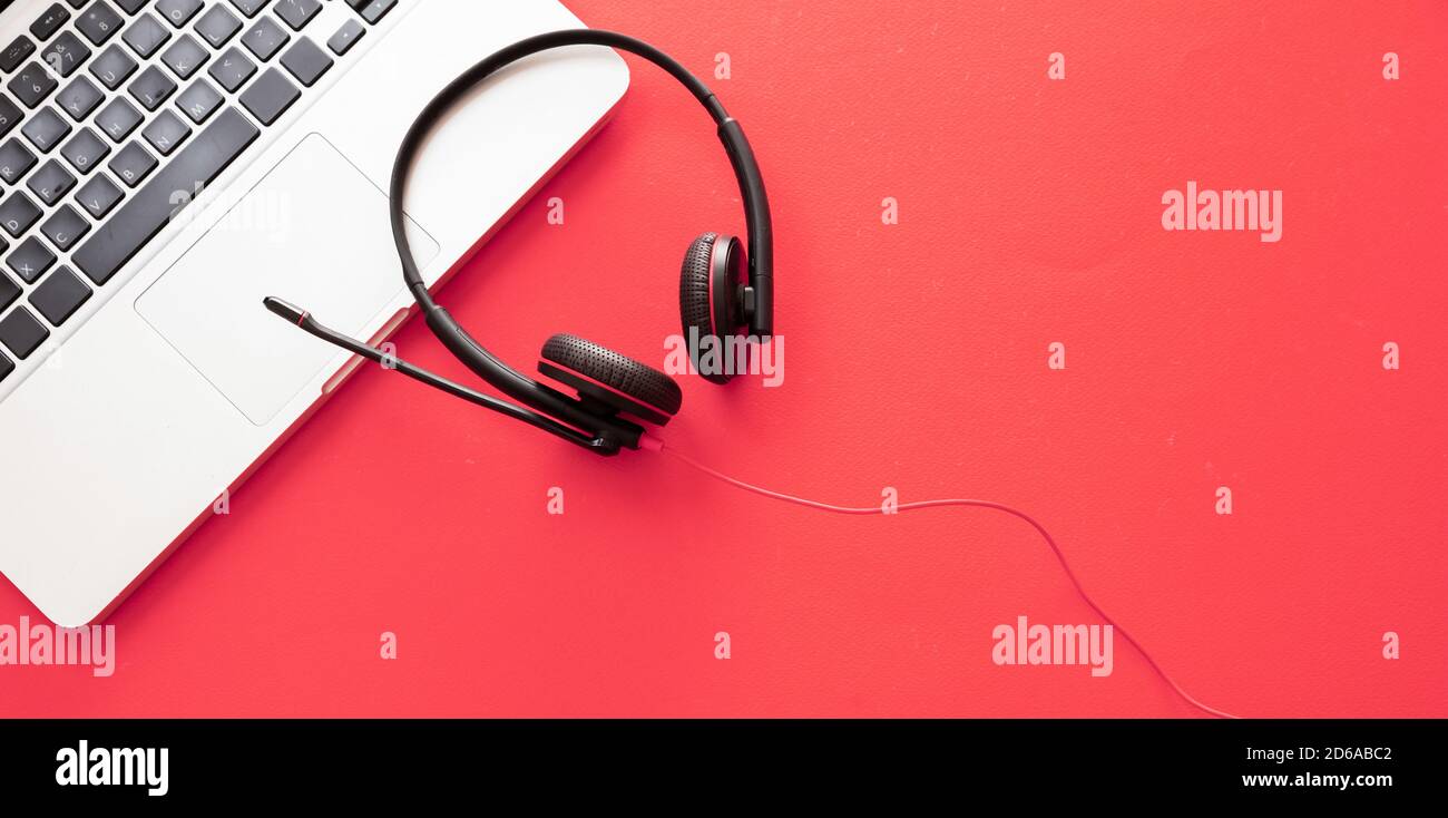 Call center and home office concept. Customer service support, help desk, communication. Headset and laptop on red background, top view, copy space, b Stock Photo