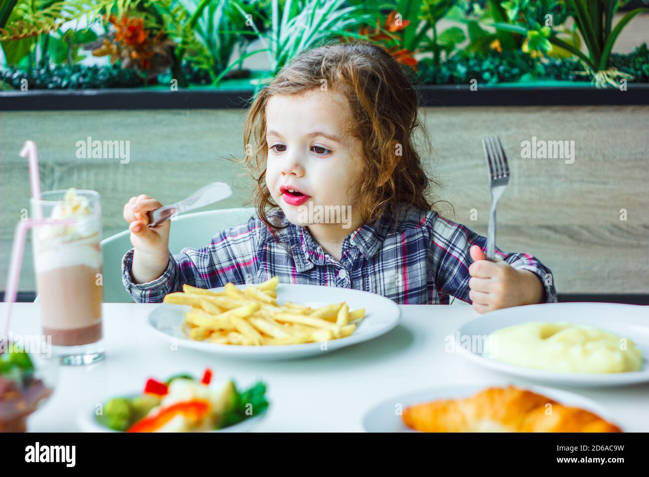 Little girl having lunch in the restaurant with the table knife and