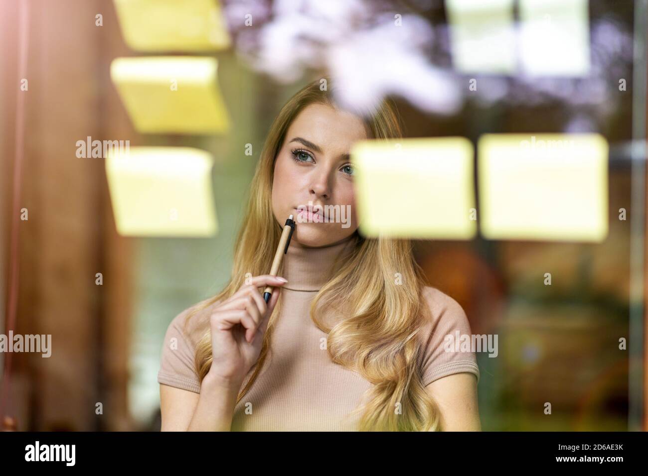 Young businesswoman brainstorming with notes on a glass wall in an office Stock Photo
