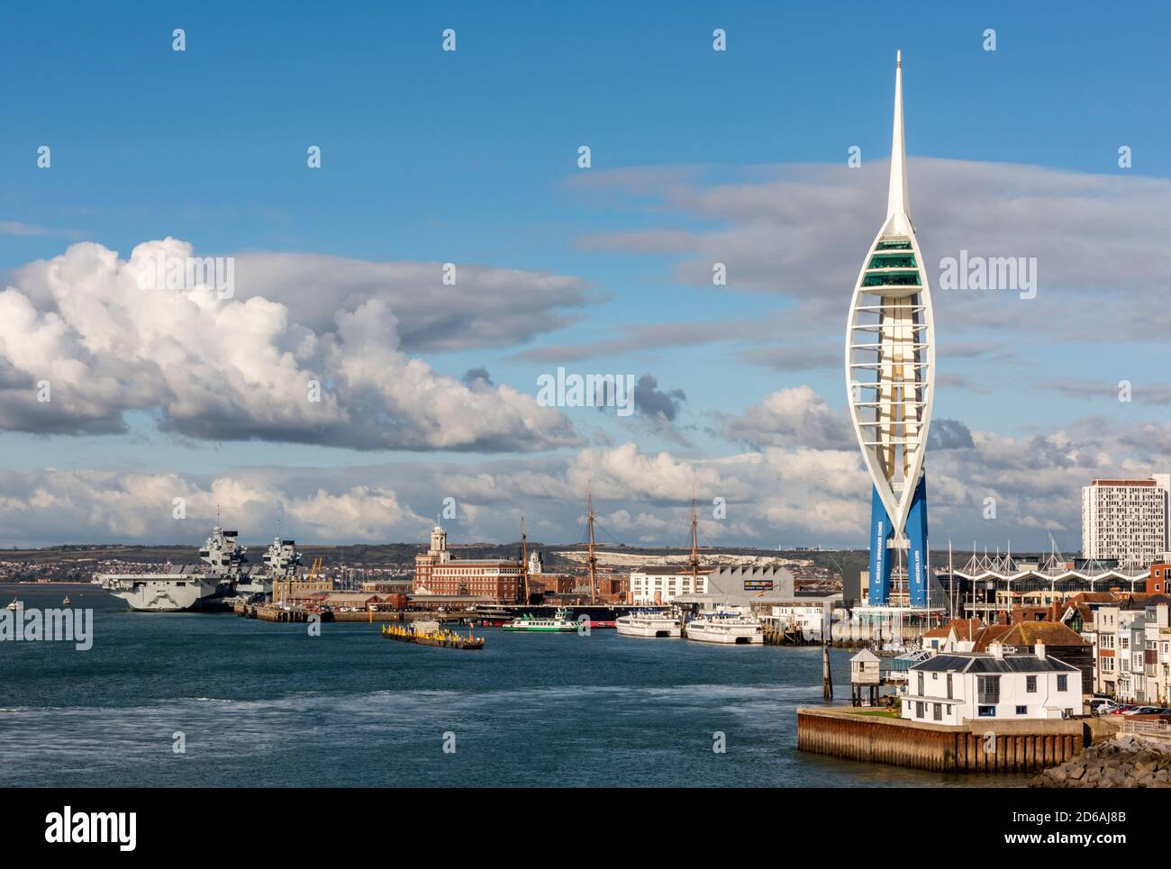 the entrance to portsmouth harbour with the spinnaker tower and hms queen elizabeth under a sky full of summer clouds. Stock Photo