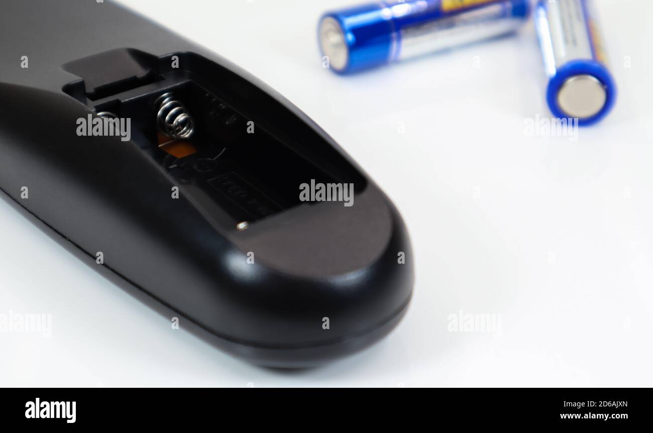 Black remote control with blue AAA batteries on a white background