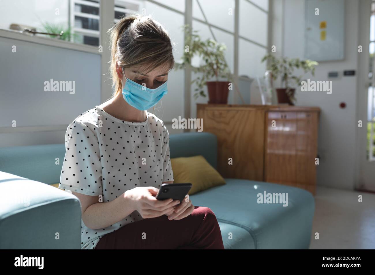 Woman wearing face mask using smartphone Stock Photo