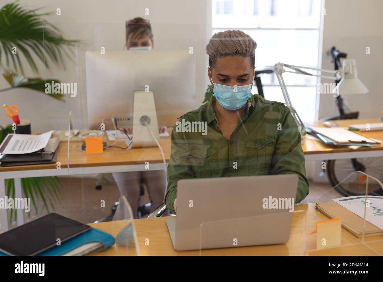 Man wearing face mask using laptop at office Stock Photo