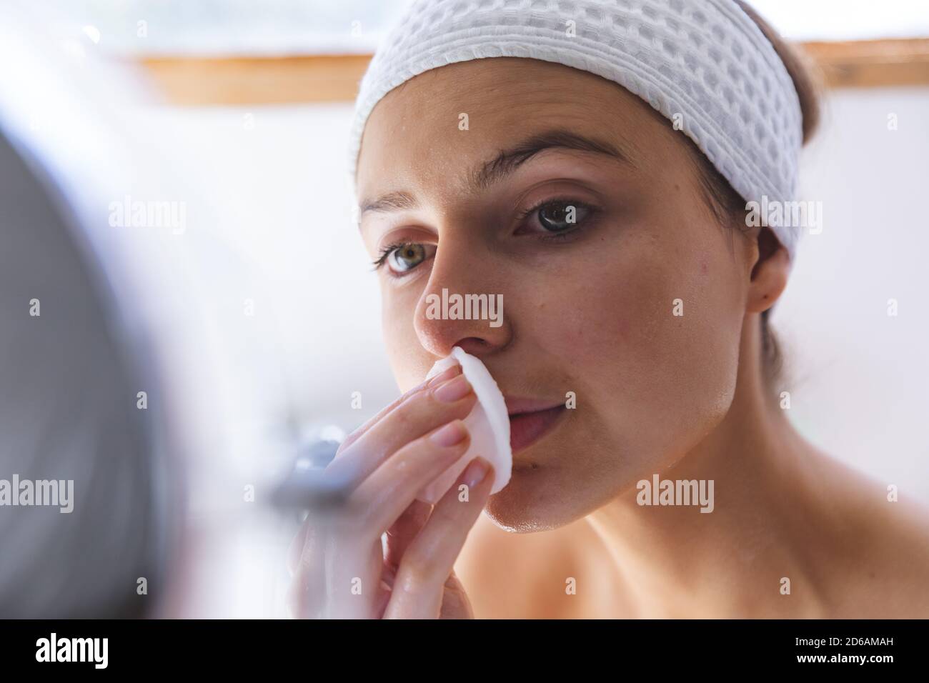 Close up of woman cleansing her face with cotton pad in bathroom Stock Photo
