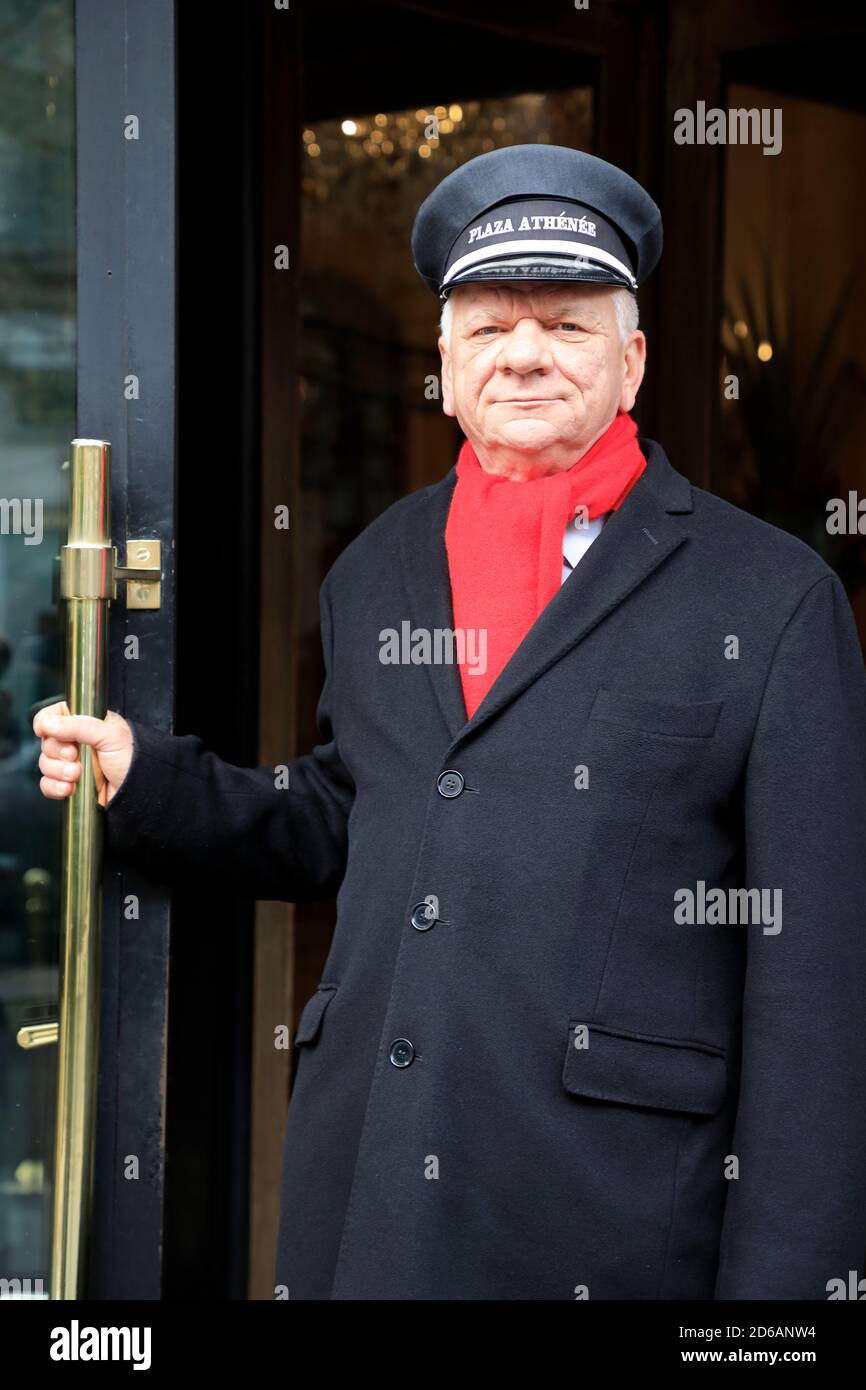 The doorman of Hotel Plaza Athénée holding the entrance door of the historic landmark Hotel Plaza Athénéel in Avenue Montaigne.Paris.France Stock Photo