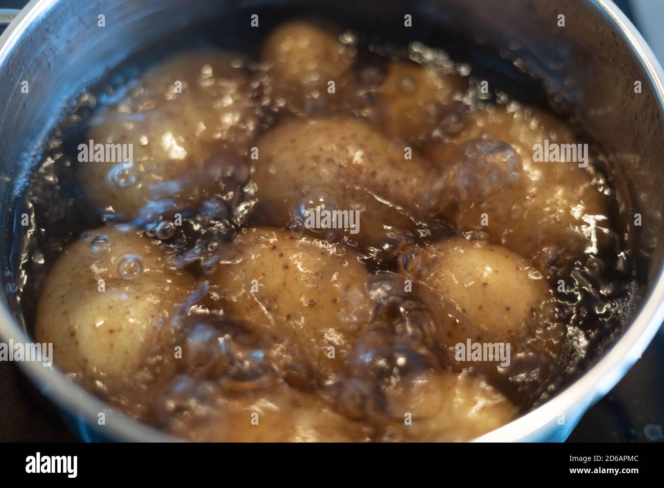 cooking potatoes in boiling water in a stainless steel pot on the stove
