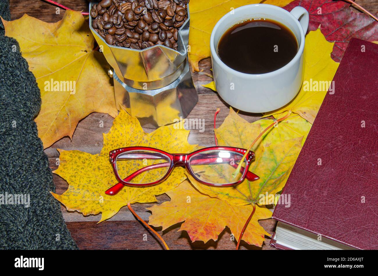 Hot coffee in red cup with steam and eyeglasses on stacked books wooden background, coffee break concept Stock Photo