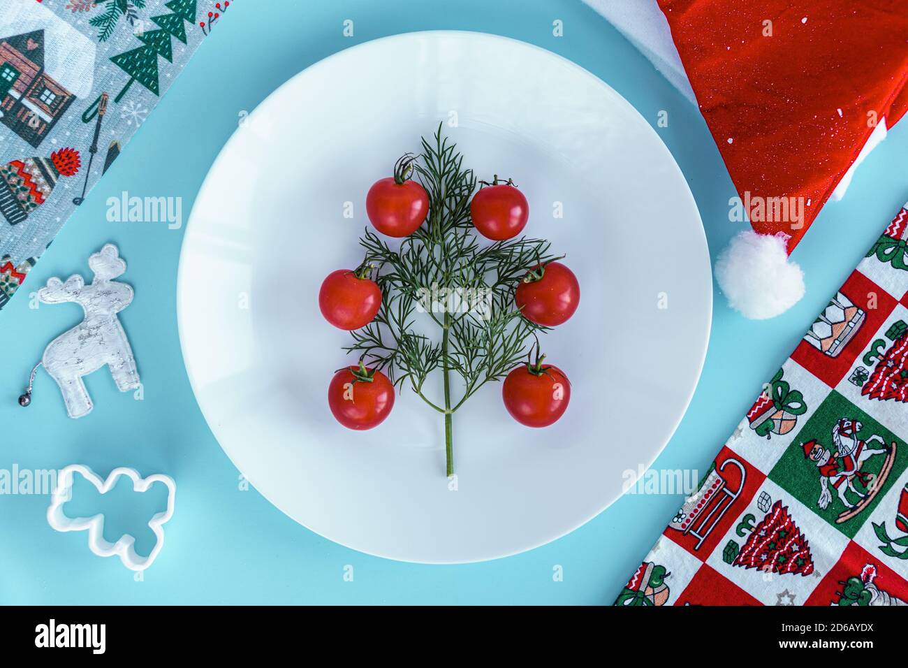 Xmas, winter, new year concept - layout white plate on which there are Christmas tree dill tree decorated with red cherry tomatoes in a triangle shape Stock Photo