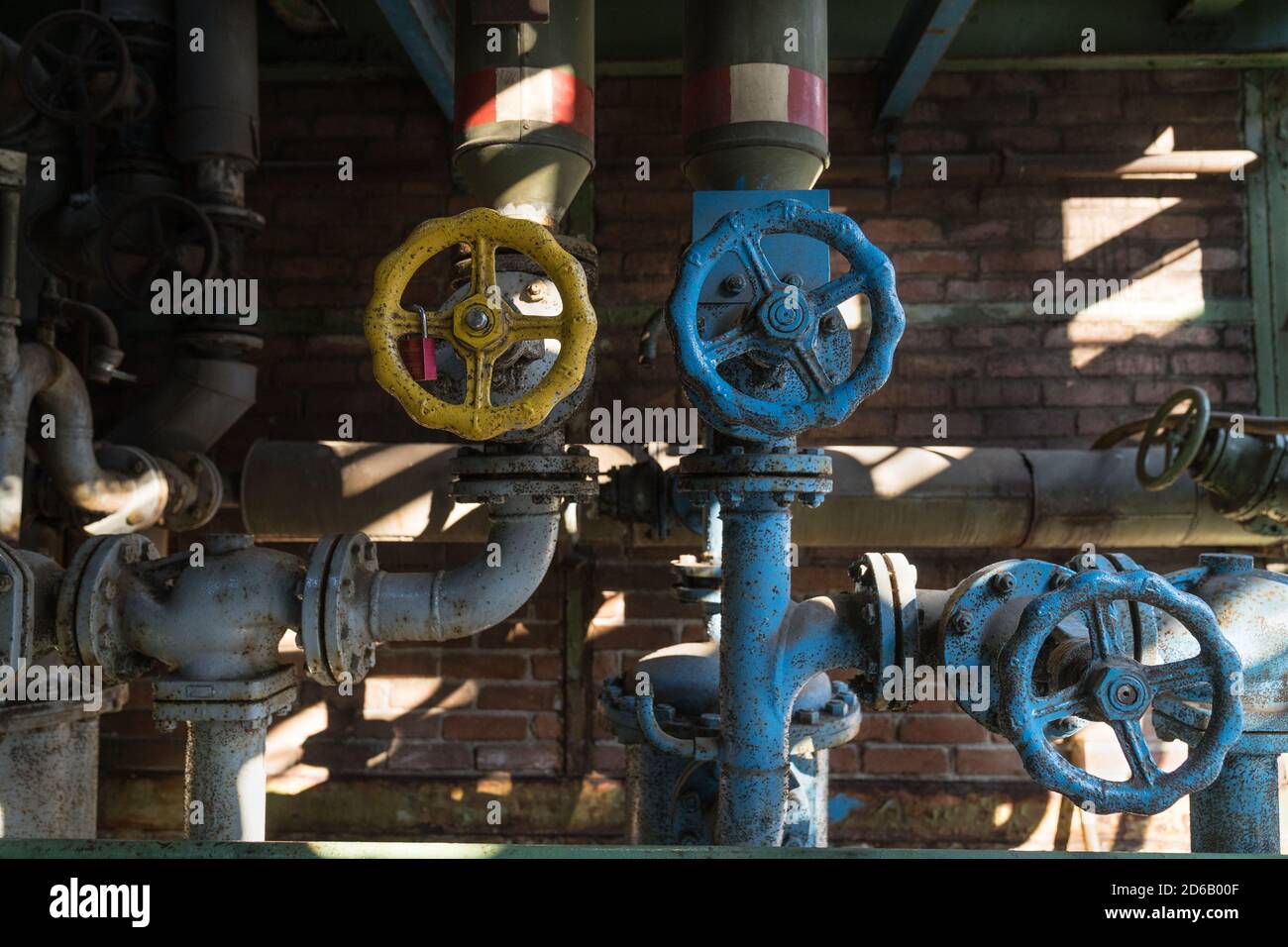 Yellow and blue pipes and valve handle wheel at the abandonned blast furnace at Duisburg Landschafts Park Germany Stock Photo