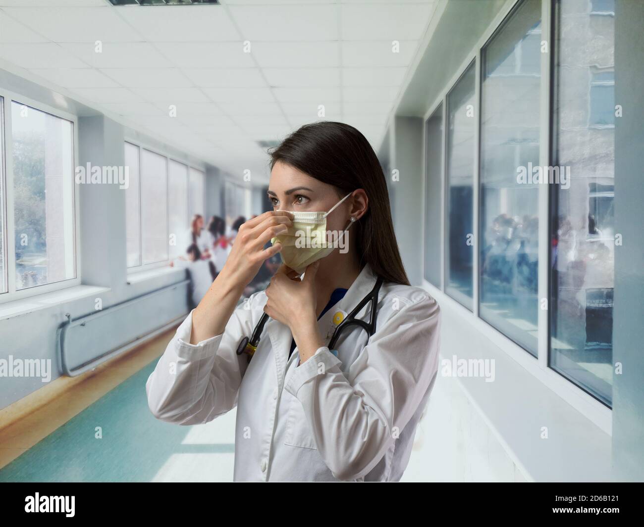 Healthcare worker in white coat putting on mask in hallway before