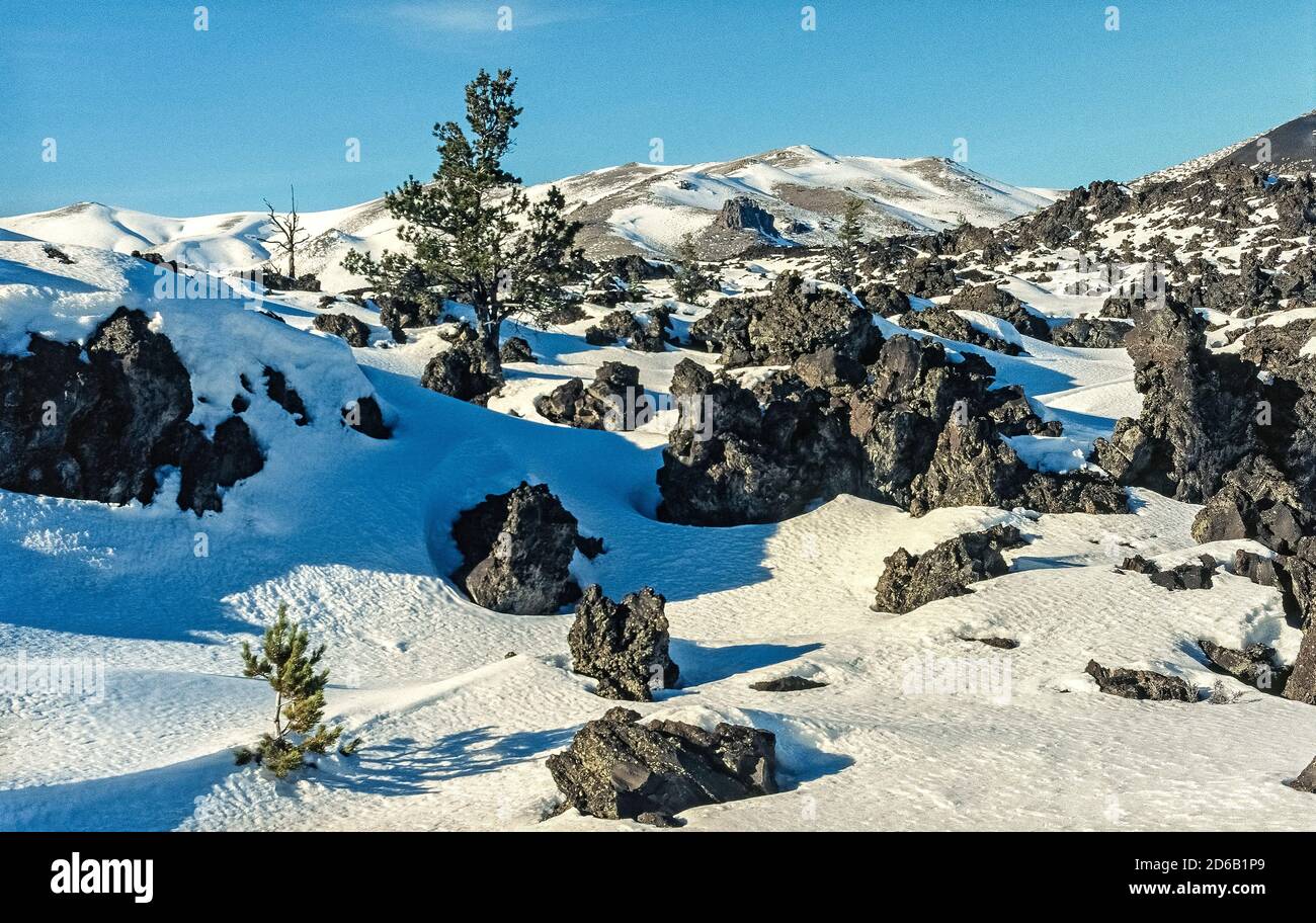 Snow covers some of the black lava formations that are among the features of Craters of the Moon National Monument and Preserve that sprawls across the Snake River Plain in Idaho, USA. This peculiar landscape is the result of eight major volcanic eruptions that began 15,000 years ago and continued until only 2,000 years ago. Geologists predict that the area will experience another eruption sometime in the next 100 to 900 years. A 7-mile (11--kilometer) loop road allows visitors to tour the preserve by car, and many trails encourage further explorations by foot. Stock Photo