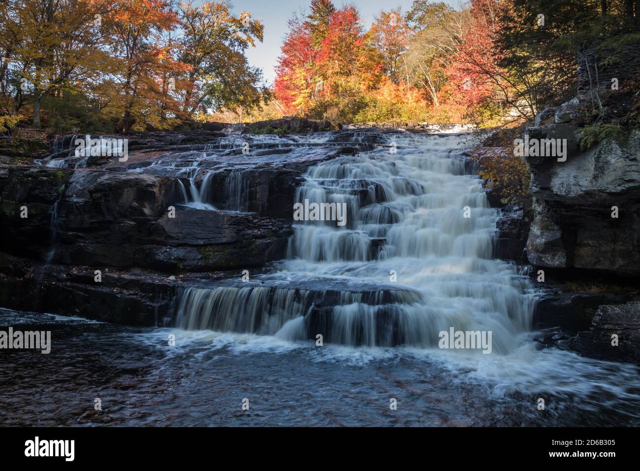 Peak fall foliage surrounds beautiful cascading Shohola Falls on an