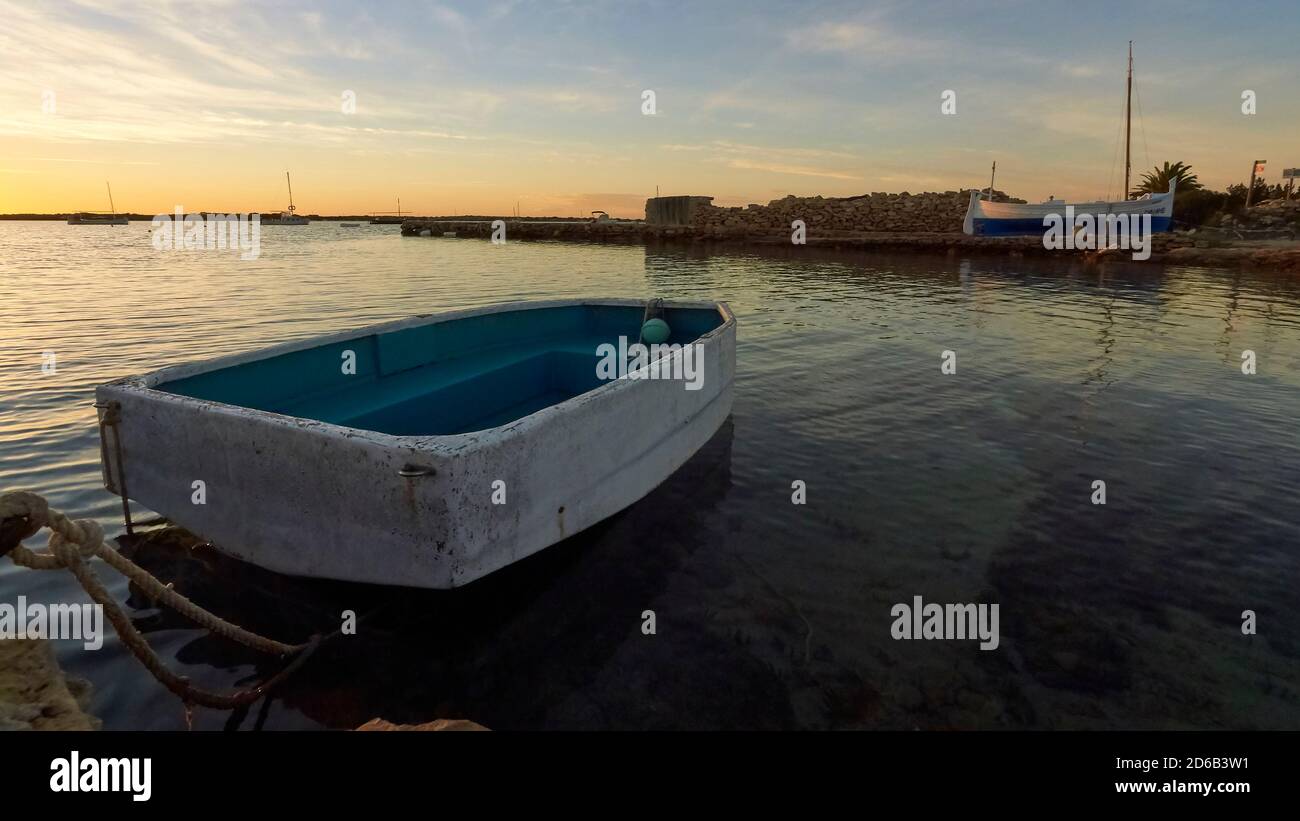 Skiff and balearic traditional fishing boat, called llaut, on a dry dock in Ses Salines Natural Park at sunset (Formentera, Mediterranean Sea, Spain) Stock Photo