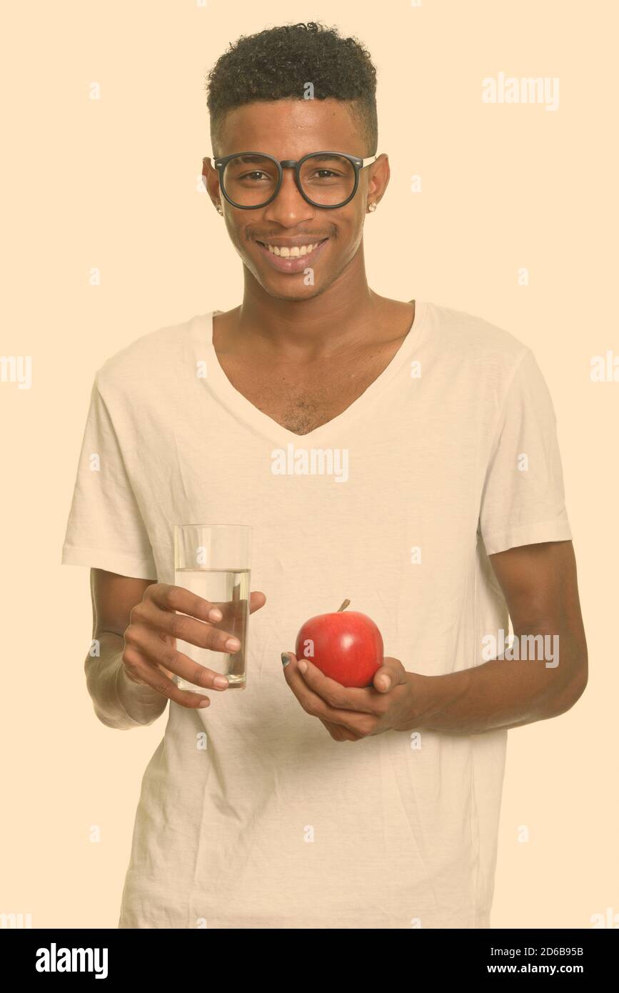 Young happy African man holding red apple and glass of water Stock ...