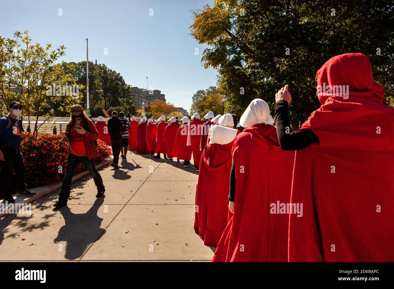 Washington, DC, USA, 15 October, 2020.  Pictured: Women and girls walk silently on the sidewalk in a single file line during the Handmaids Descend on the Supreme Court protest held by Refuse Fascism DC.  For the event, women dressed as handmaids in red capes from The Handmaid's Tale and stood in front of the Supreme Court building to protest the nomination of Amy Coney Barrett and fascist policies of the Trump Administration.  The protest continued Refuse Fascism's demand for immediate removal of Donald Trump and Mike Pence from office.  Credit: Allison C Bailey/Alamy Live News Stock Photo