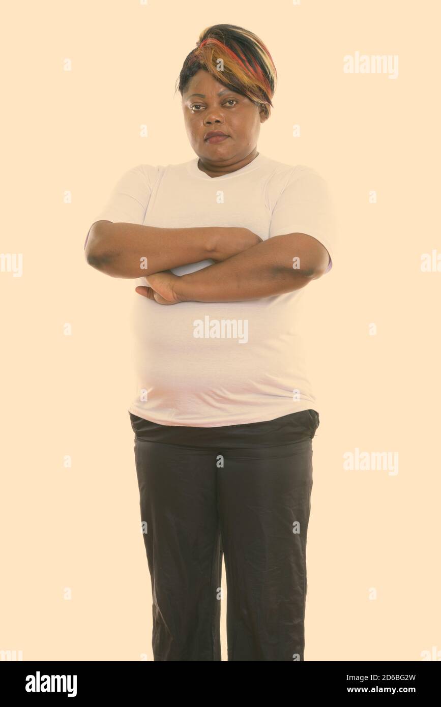 Studio shot of fat black African woman standing with arms crossed ready ...