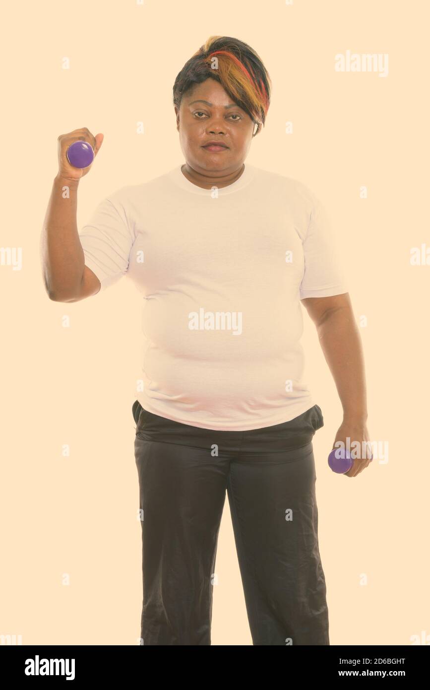 Studio shot of fat black African woman standing while exercising with  dumbbells ready for gym Stock Photo - Alamy