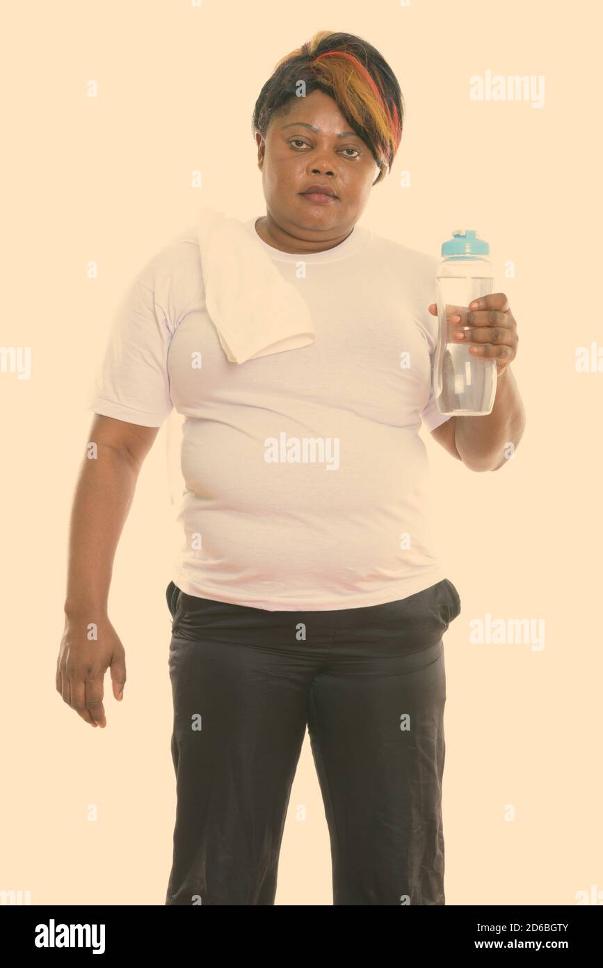 Studio shot of fat black African woman standing while holding water ...