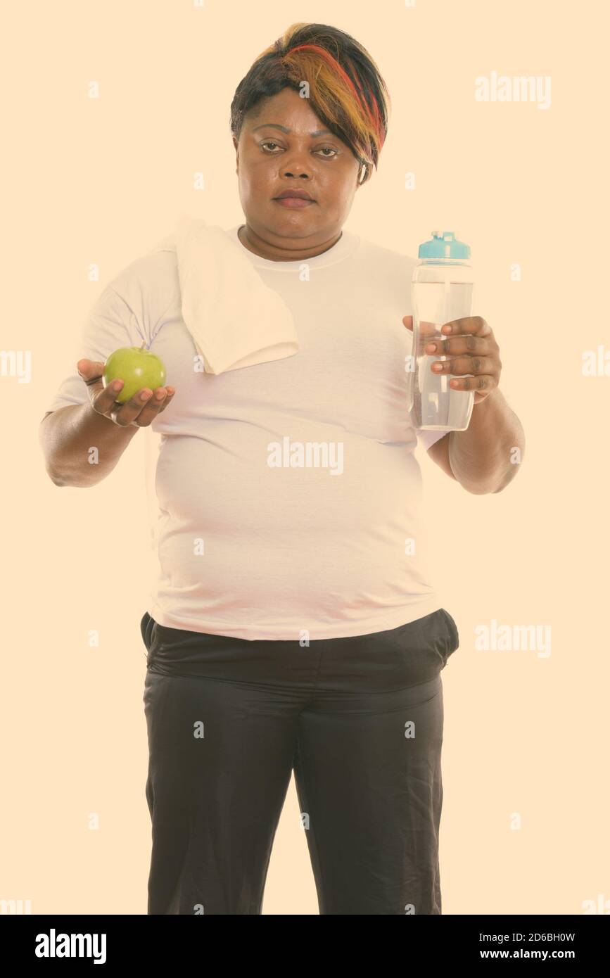 Studio shot of fat black African woman standing while holding water ...