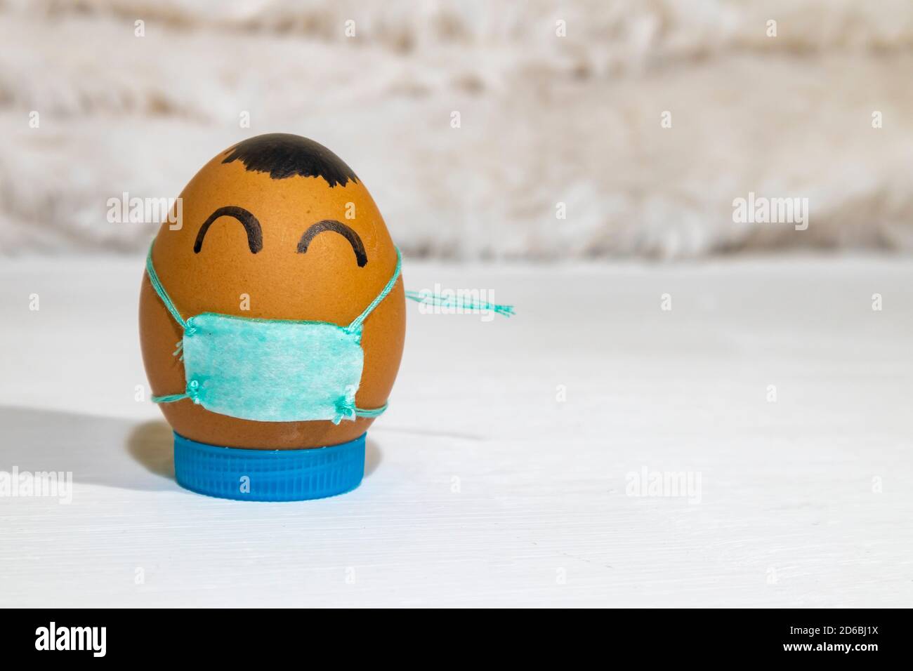 A painted egg wearing mask. Covid-19 illustration. Fun activity with children. Stock Photo