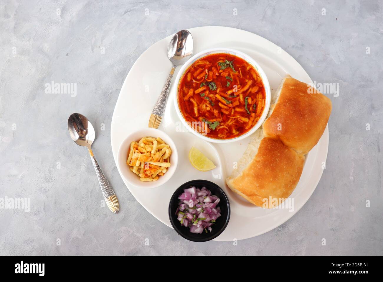 Spicy Misal Pav or usal Pav is a traditional snack or Chaat food from Maharashtra, India. Served with chopped onion, lemon wedges and farsan. Stock Photo
