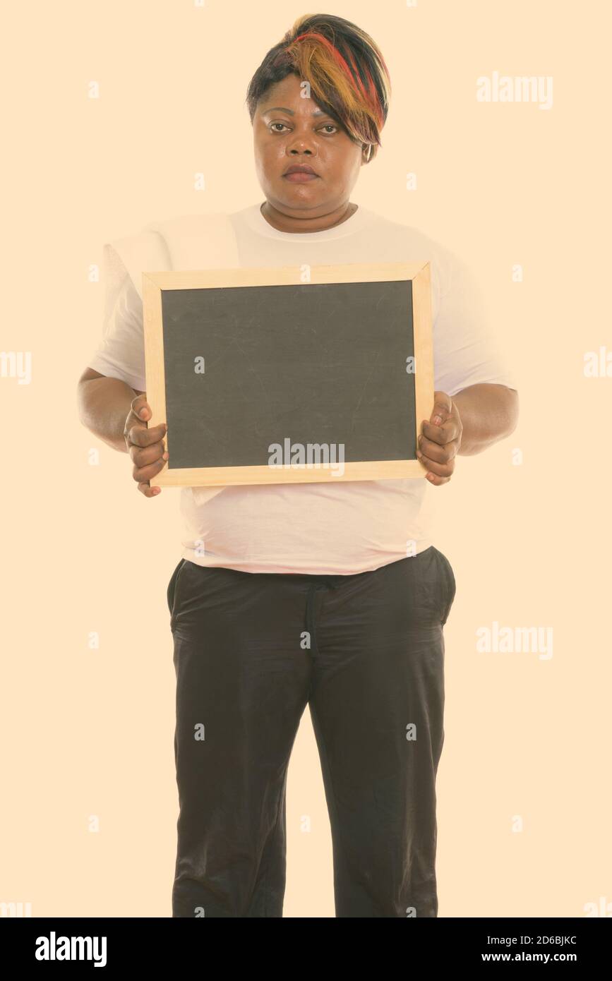 Studio shot of fat black African woman standing while holding blank ...