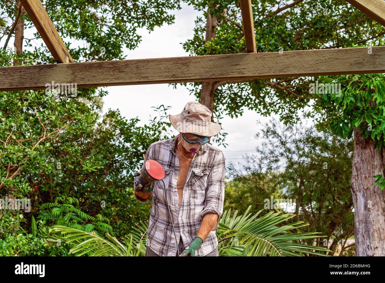 Townsville, Queensland, Australia - June 2020: Man standing sanding and repairing timber roof rafters of residential house Stock Photo