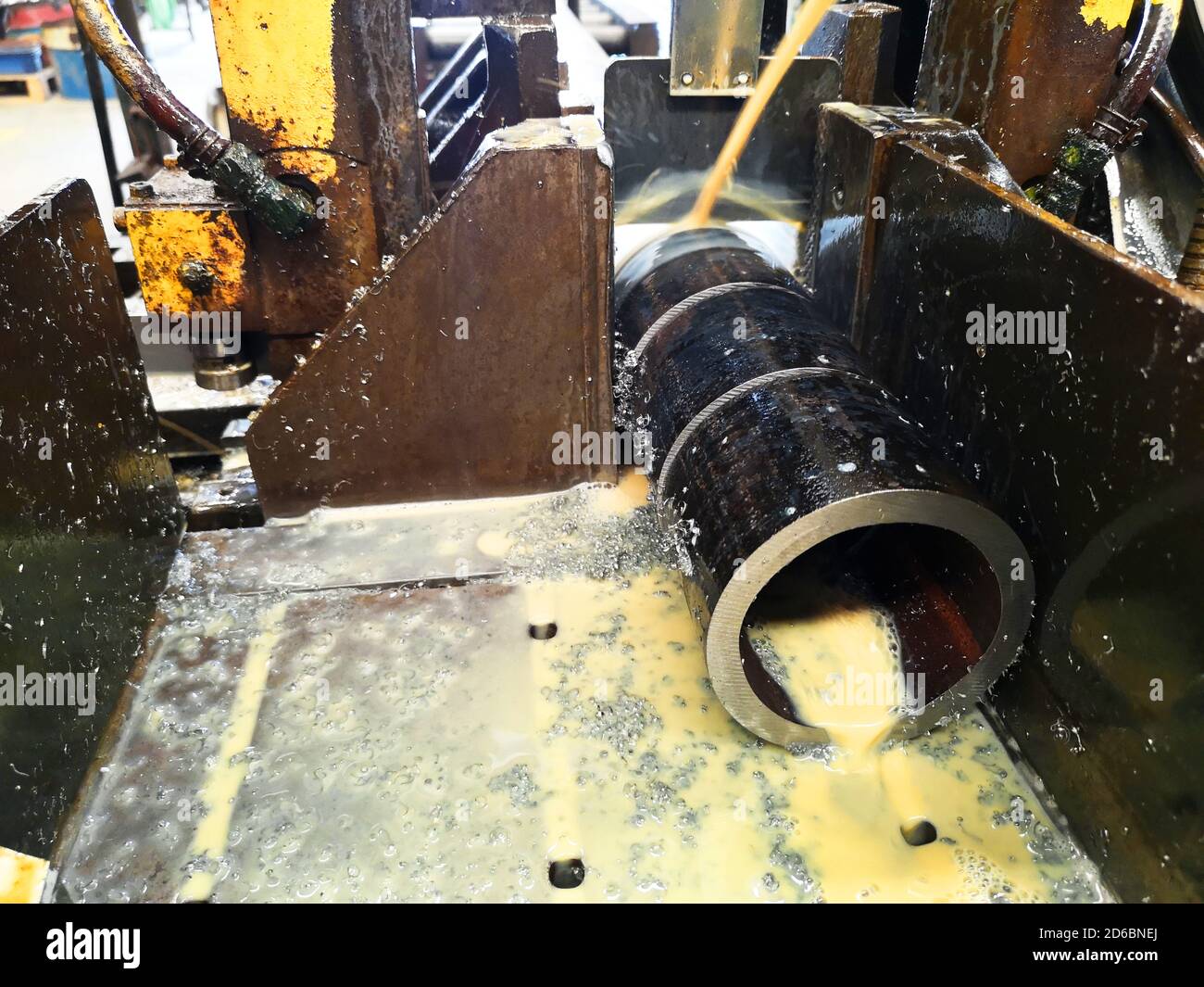 Industrial band saw, metal tube cutting, coolant in black, industrial