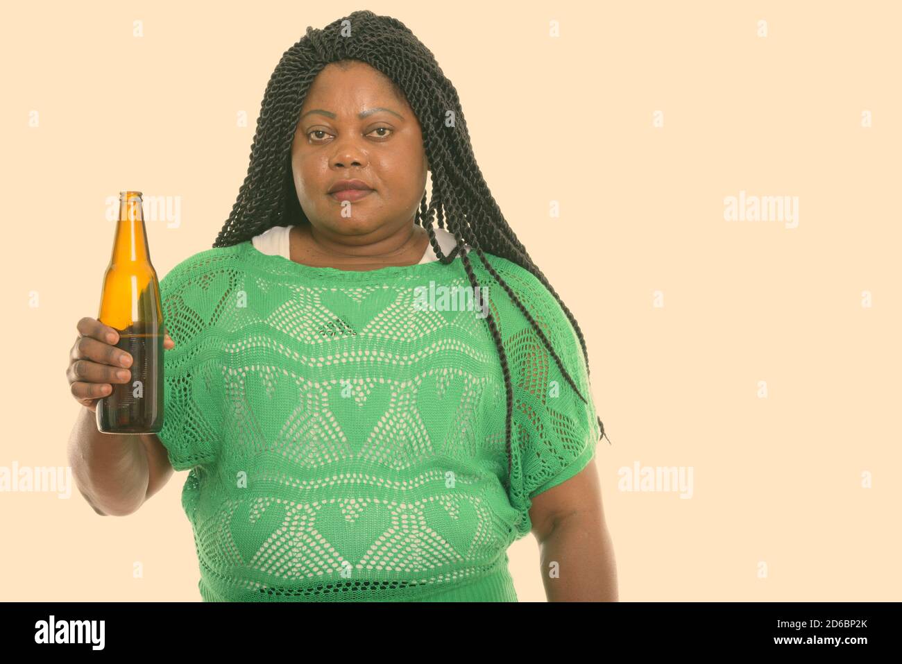 Studio shot of fat black African woman holding bottle of beer Stock Photo