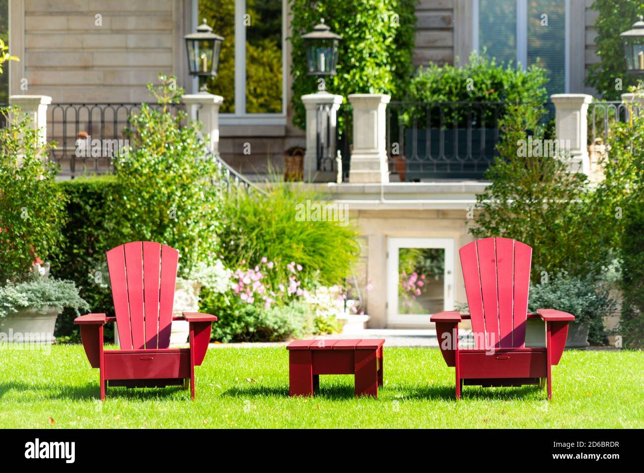 Red garden furniture on a lawn with a stately mansion in the background