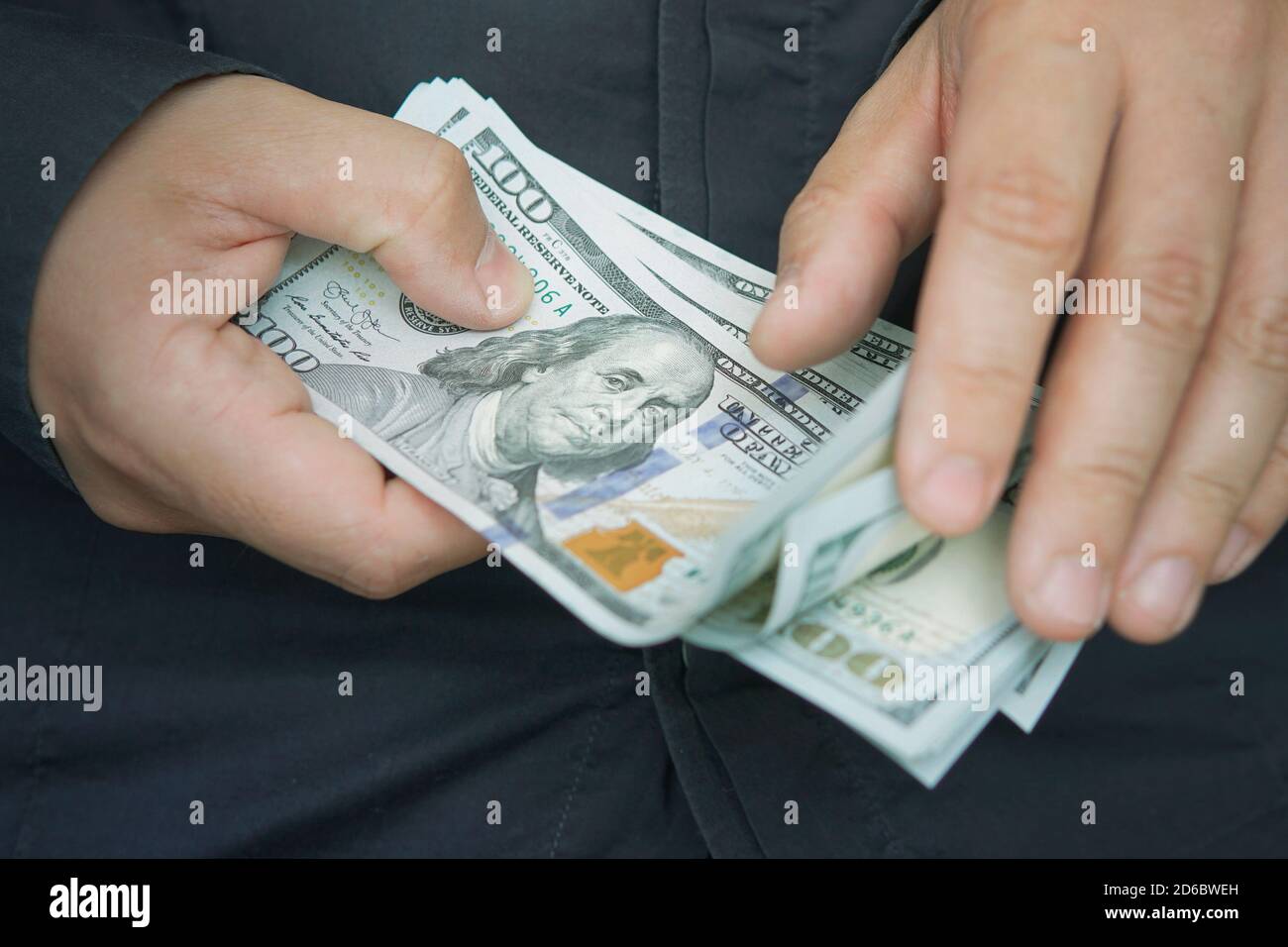 A male employee counts the salary in dollars, close-up. Cash for pocket expenses. Tips in 100 bills. counting. money with hands Stock Photo