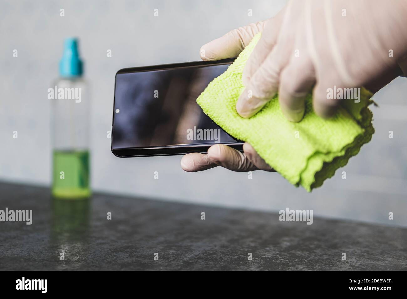 man wipes his mobile phone with a rag. Disinfecting alcohol solution for killing germs on gadgets. method of protection against infections of viruses Stock Photo