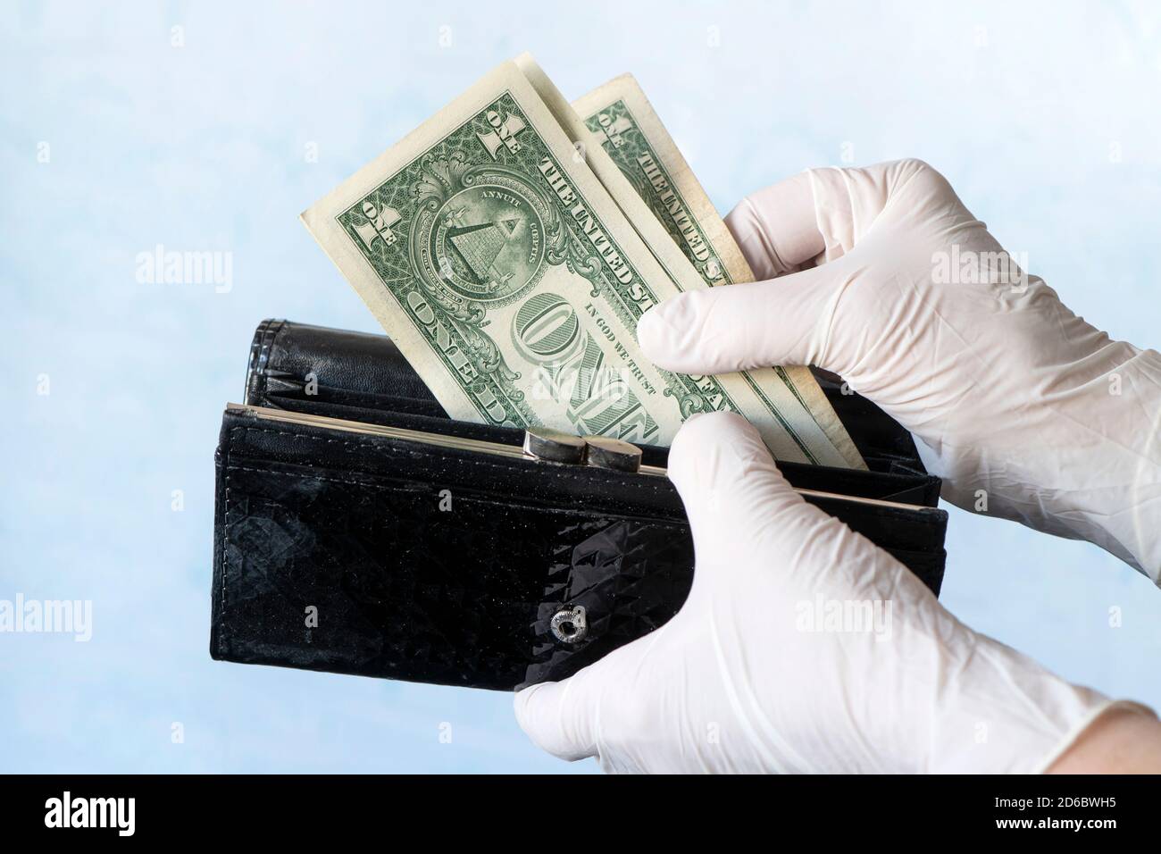 woman taking money out female wallet wearing rubber gloves to prevent the spread of bacterias or viruses, take shopping during coronavirus pandemic Stock Photo