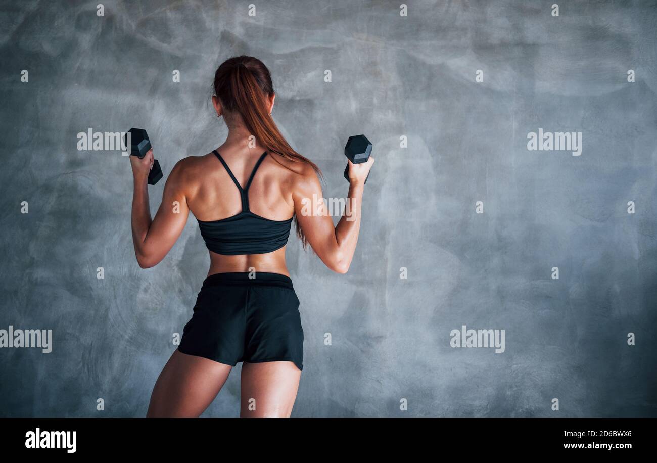 Young fitness woman is in the gym near wall with dumbbells in hands  15239117 Stock Photo at Vecteezy