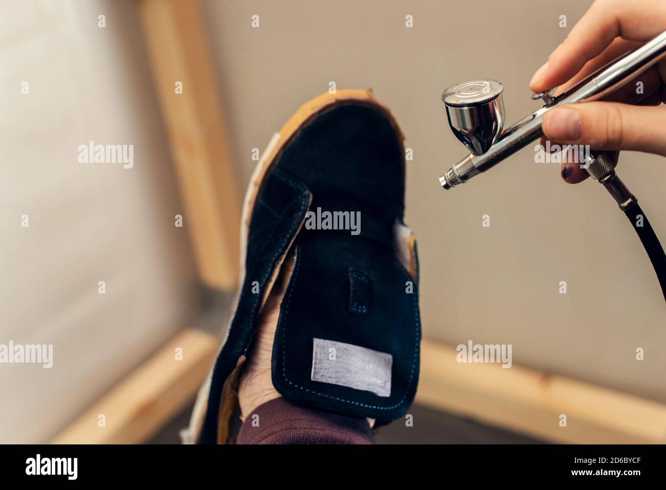 Painting and restoring suede blue sneakers with an airbrush at a workshop repairman. Stock Photo