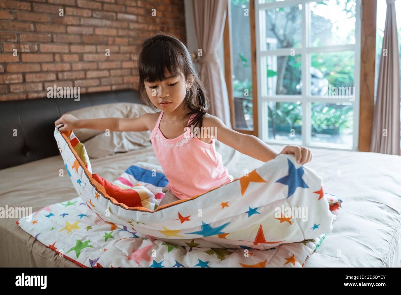 independent asian child make up her room and fold the blanket Stock