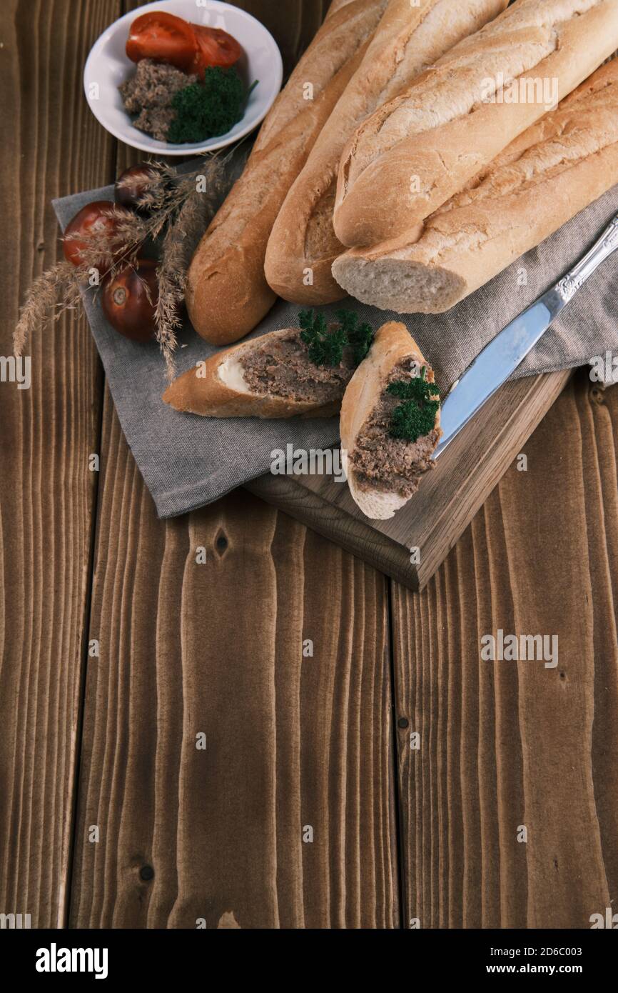 Top view fresh French baguette sliced with foie gras tomato and parsley on a wooden table Stock Photo