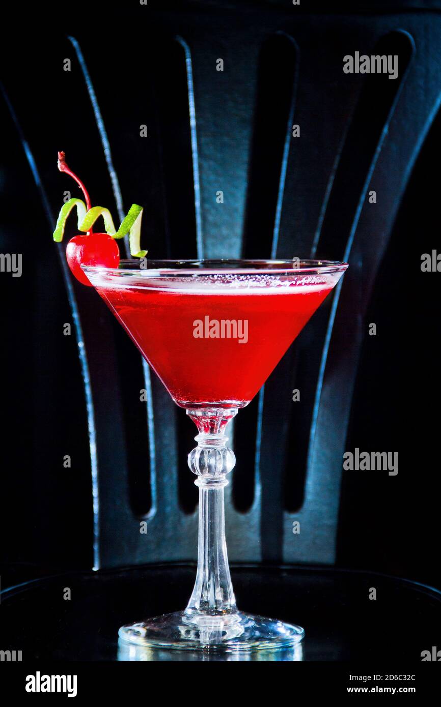 Red drink cocktail with cherry in martini glass, cherry and lime peel. Stock Photo