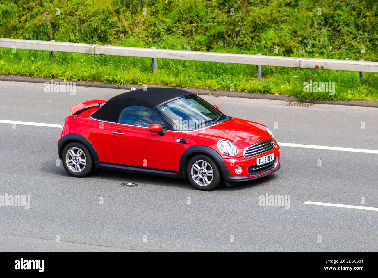 2012 red Mini  Roadster Cooper; Vehicular traffic, moving vehicles, cars, vehicle driving on UK roads, motors, motoring on the M6 motorway highway UK road network. Stock Photo