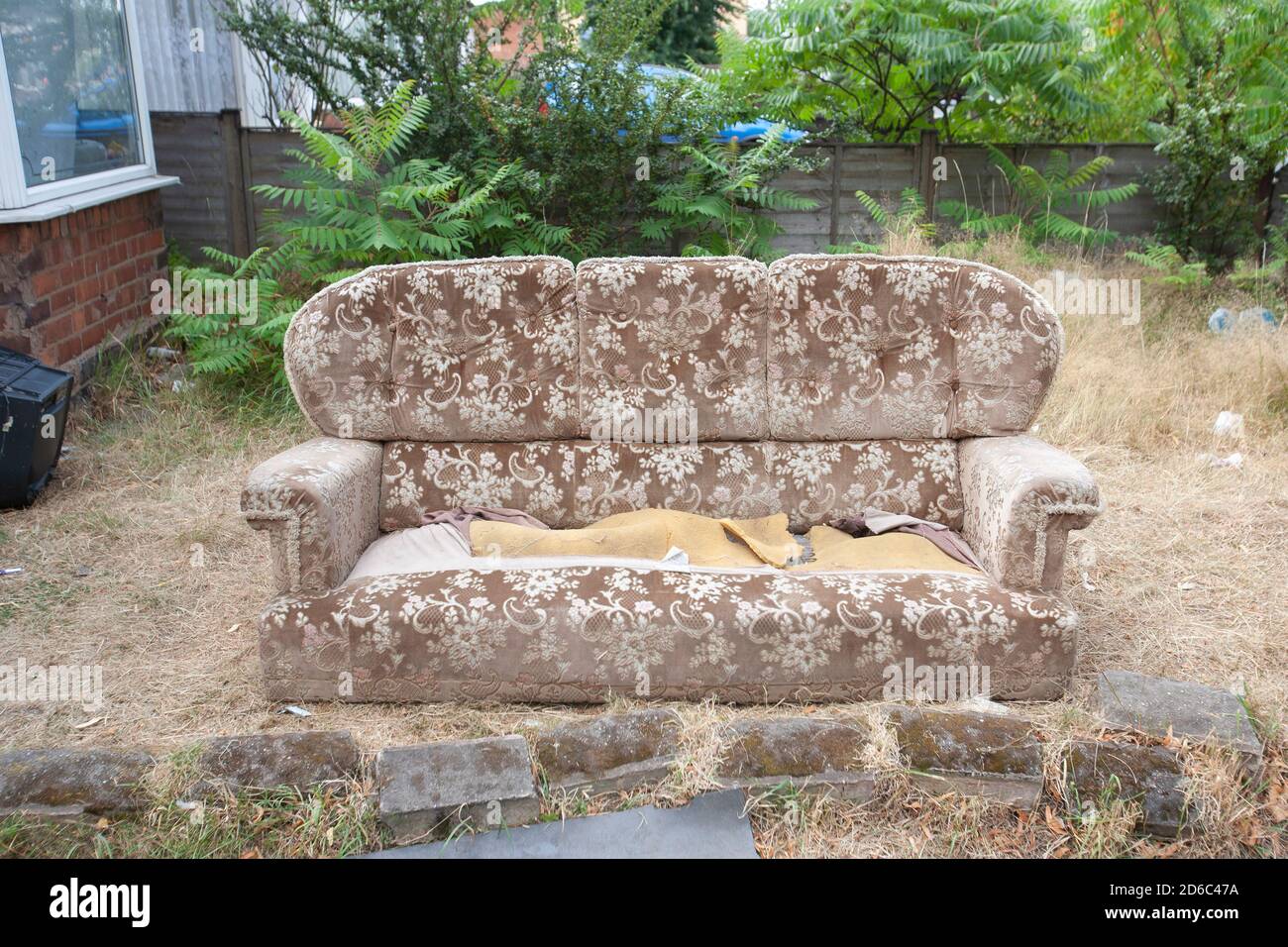 An abandoned sofa in a front garden in Birmingham, UK Stock Photo