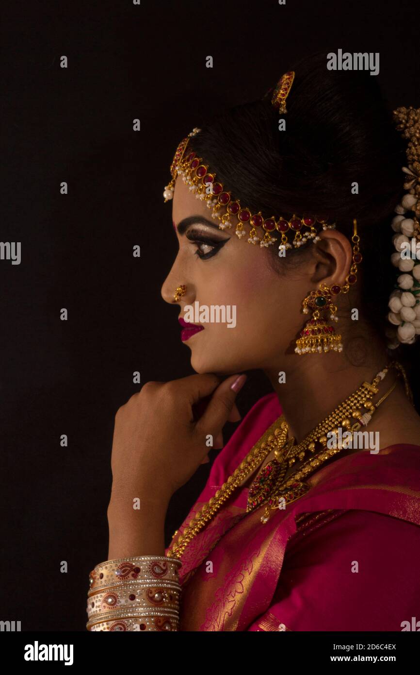 Young South Indian model in bridal red sari with golden jewelry set. Side profile Stock Photo