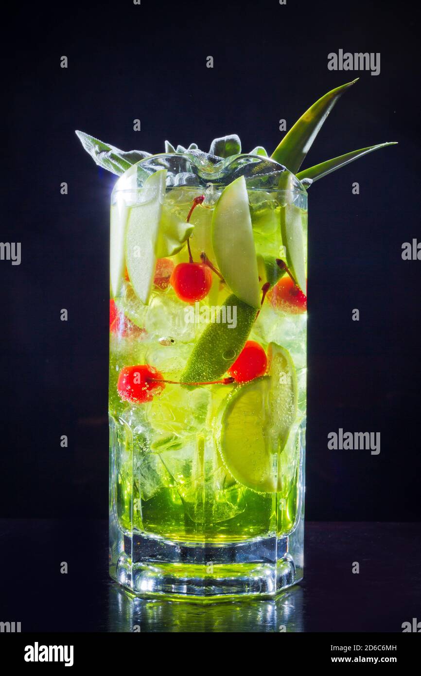 Green drink cocktail with apple, lime and cherry in big jar for big company, closeup isolated on black background. Stock Photo
