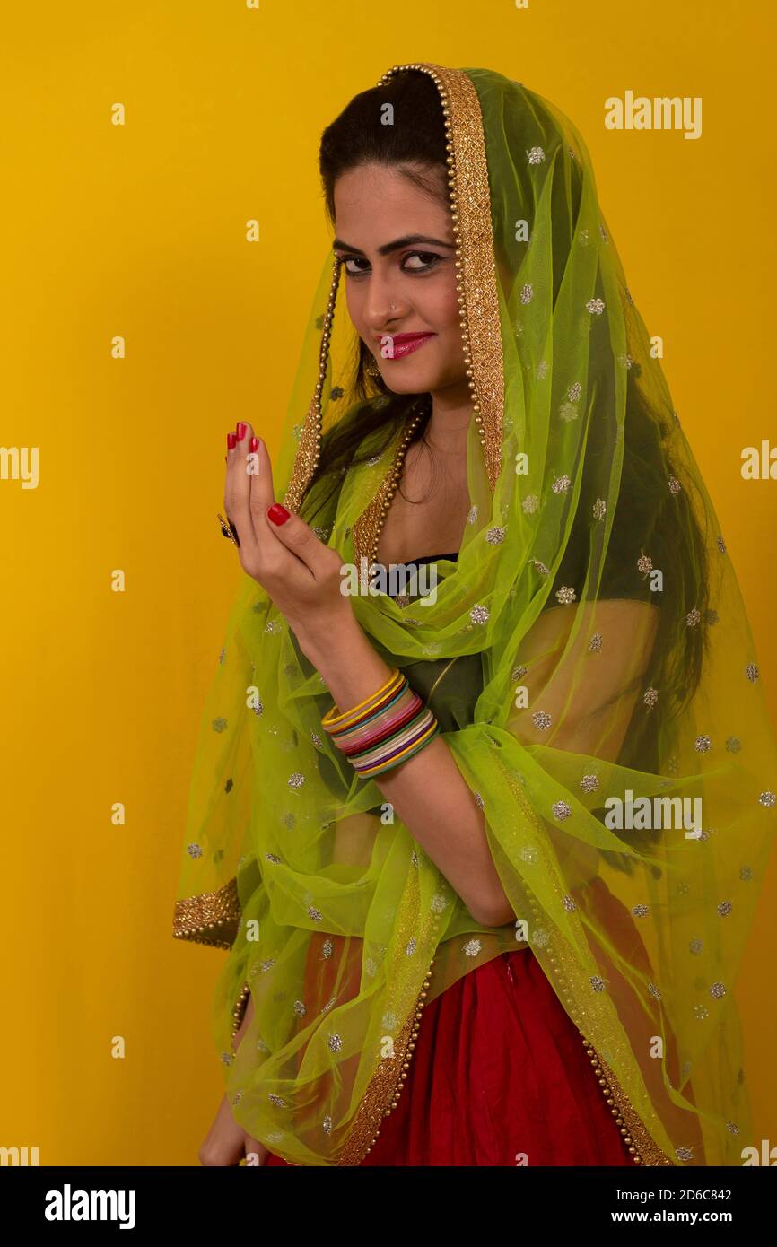 Young Indian female model in Ghagra Choli and long hair looking at camera. Hand in welcome pose Stock Photo