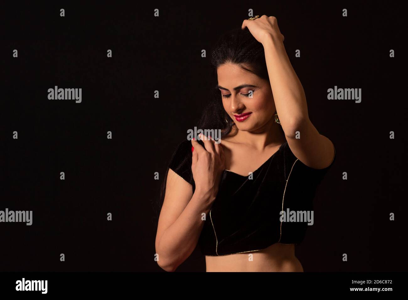 Young Indian female model with eyes closed and hand on head. Black background Stock Photo