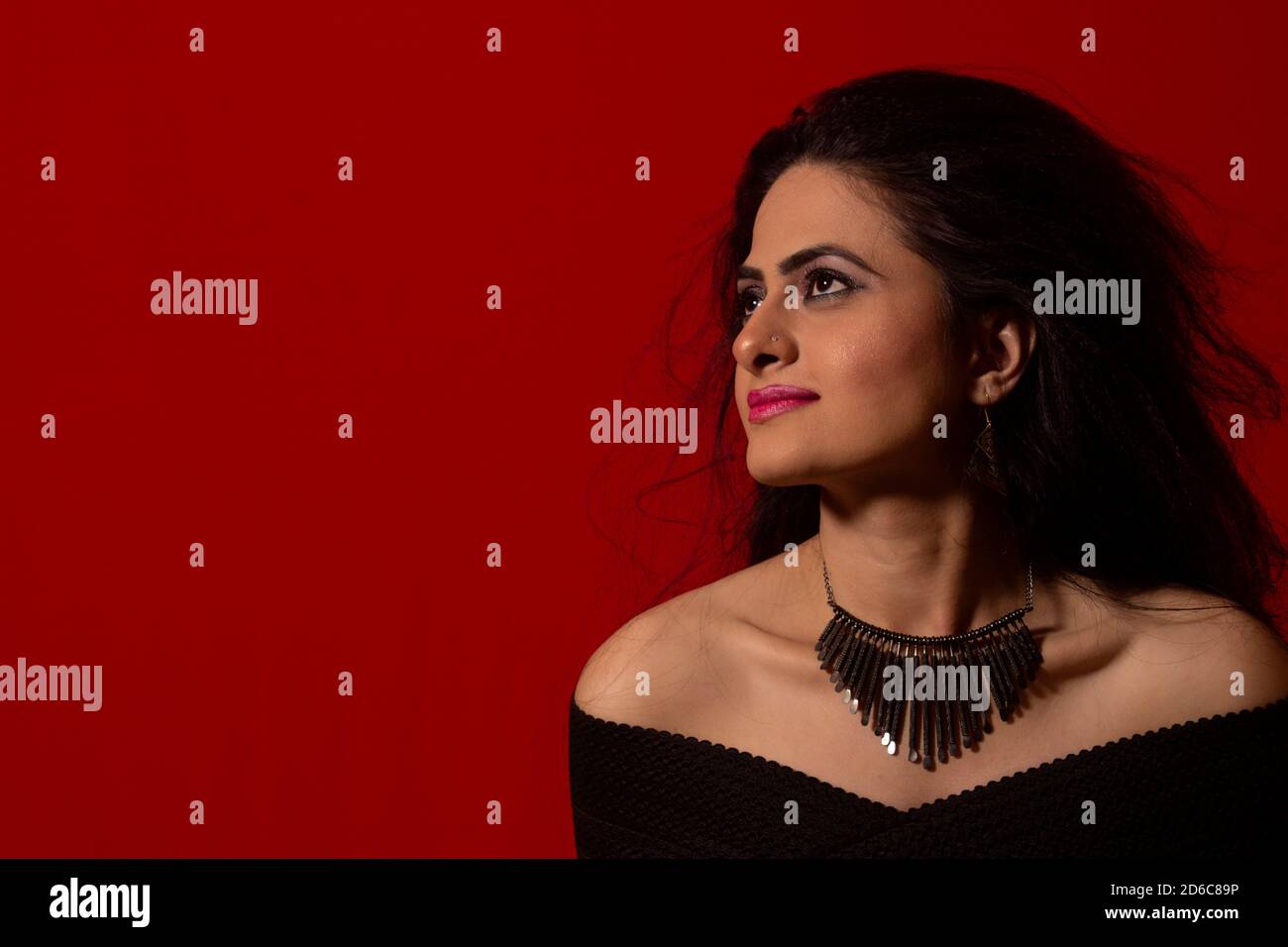 Young Indian female model looking away from camera. Red background Stock Photo