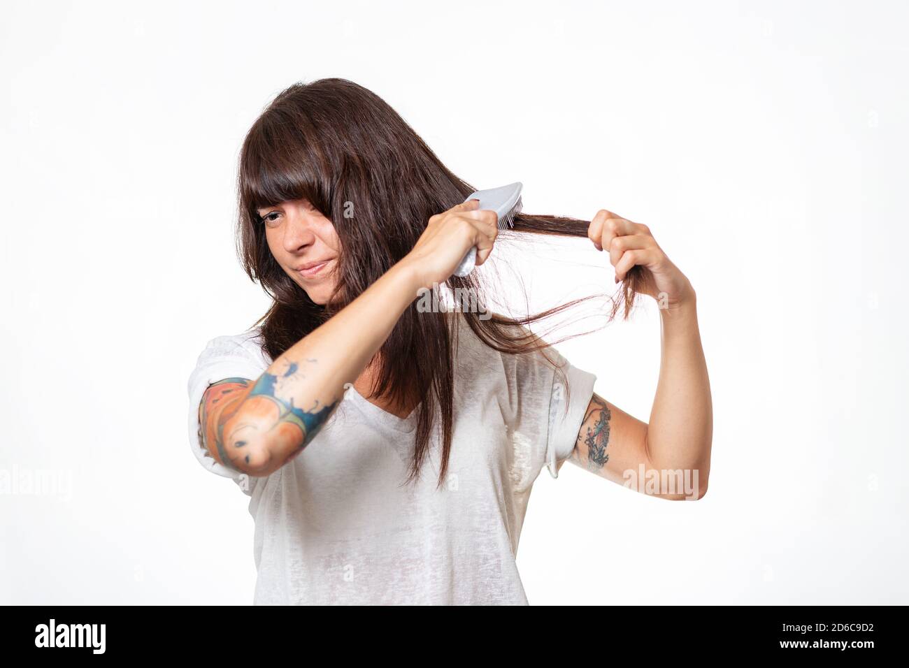 A woman with tattoos combs a lock of hair, experiencing pain and pulling out  her hair. White background. Copy space. The concept of hair loss and care  Stock Photo - Alamy